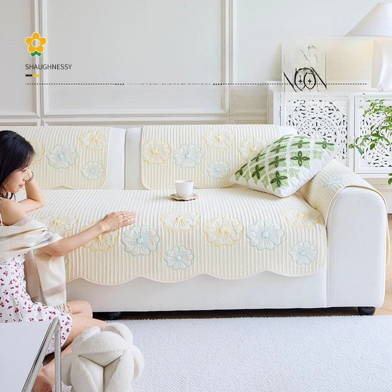 Cette image montre un canapé recouvert d'une housse fleurie, dans un intérieur lumineux avec des décorations murales, créant une atmosphère calme et apaisante.