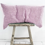 Une paire d'oreillers mauves reposant sur un tabouret en bois vintage.