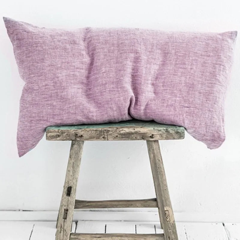 Une paire d'oreillers mauves reposant sur un tabouret en bois vintage.