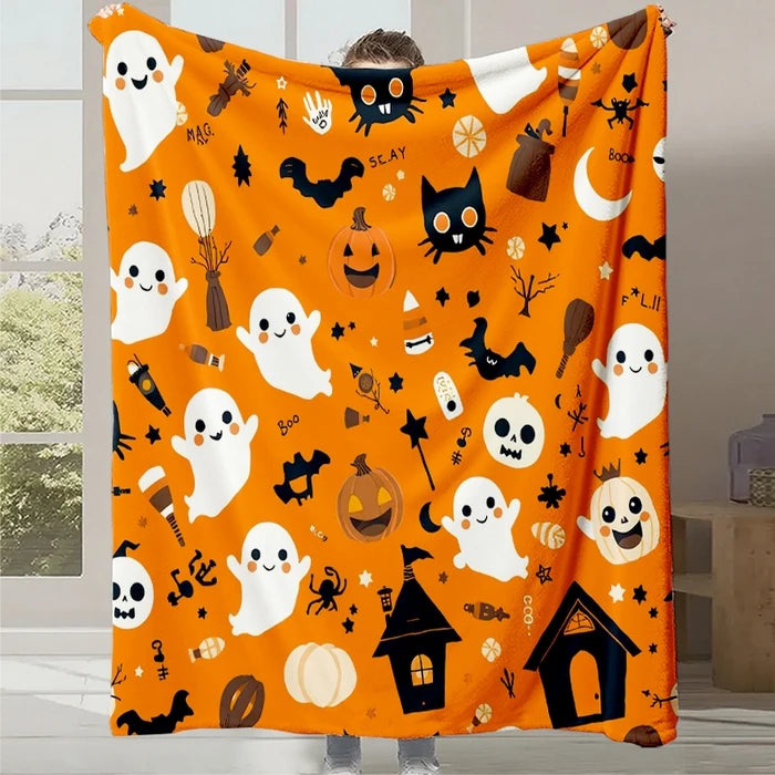 Une couverture en orange vif ornée de motifs d'Halloween, avec des fantômes, des citrouilles, des chauves-souris et d'autres symboles festifs.