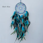 Un capteur de rêves aux plumes de paon nuancées de bleu et noir, orné de perles et de pierres précieuses, créant une œuvre d'art ethnique aux couleurs profondes.