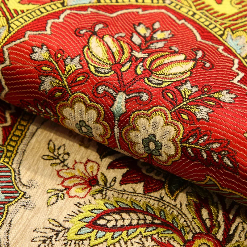 L'image montre un motif floral coloré et détaillé sur un tissu, mettant en valeur des tons rouge vif, jaune et beige dans un style traditionnel.