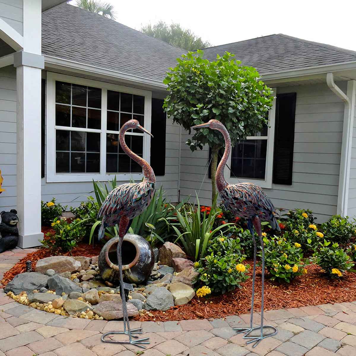statues oiseaux grue marron rouge gris vert métal patiné jardin decoratif fleurs tulipes plantes
