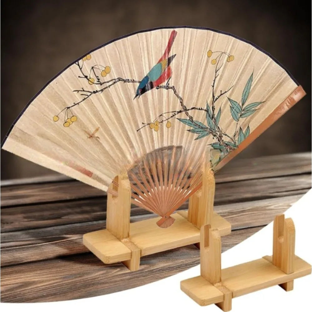 éventail pliant naturel artisanal oiseau feuilles fond beige support bois traditionnel decoration intérieure vintage