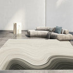 Un tapis ondulé de tons neutres, posé sur un sol en carrelage gris, avec un canapé assorti et des éléments de décoration épurés, créant une atmosphère épurée et harmonieuse dans cette pièce.
