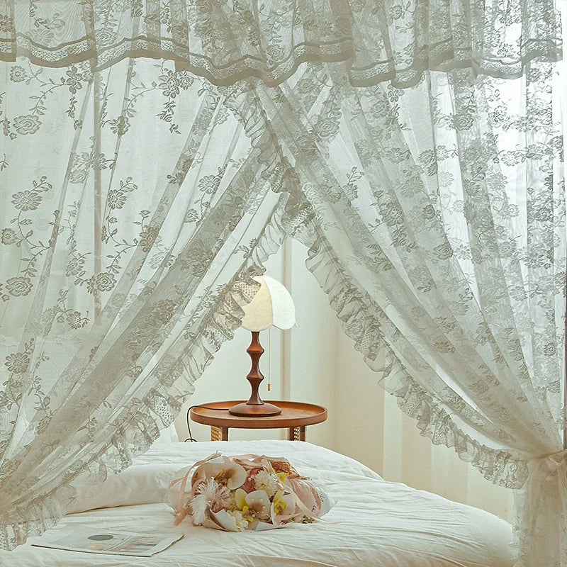 Une chambre intime et romantique avec des rideaux en dentelle formant un canopé au-dessus du lit, une table de chevet et une élégante lampe de table.