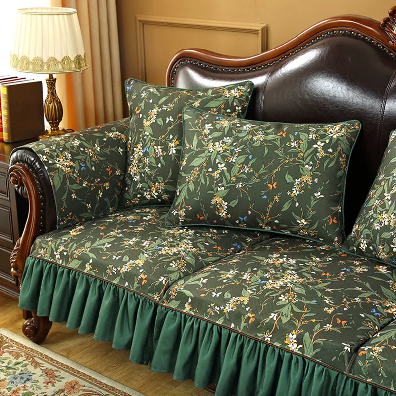 Un canapé en cuir foncé avec des coussins et une housse fleuris dans des tons de vert, de jaune et de bleu, dans un intérieur élégant et confortable.