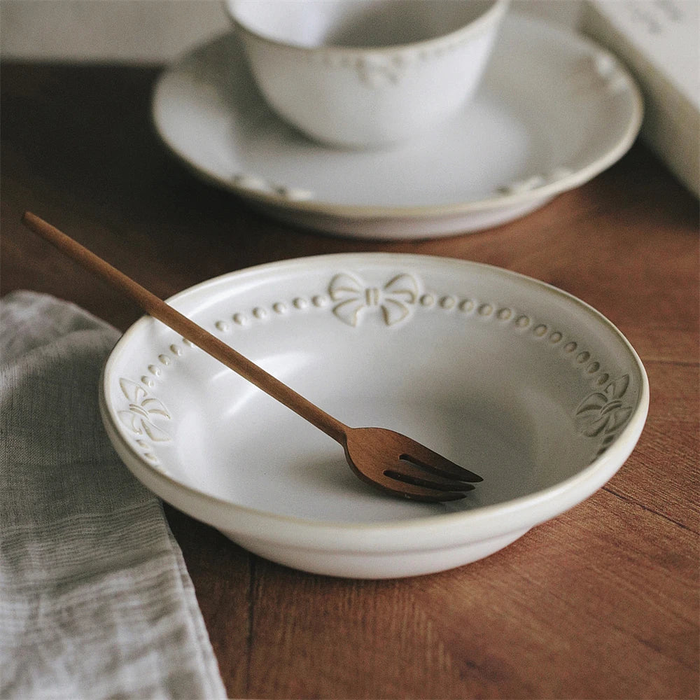 Un bol blanc avec un motif élégant et une fourchette en bois posés sur une surface en bois sombre, évoquant une atmosphère cosy et raffinée.