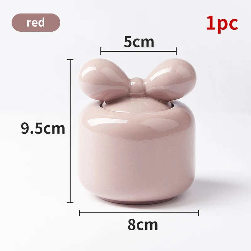 Un joli bol en céramique rose poudré avec un nœud papillon en relief sur le couvercle, créant une jolie décoration d'intérieur ou un contenant décoratif.