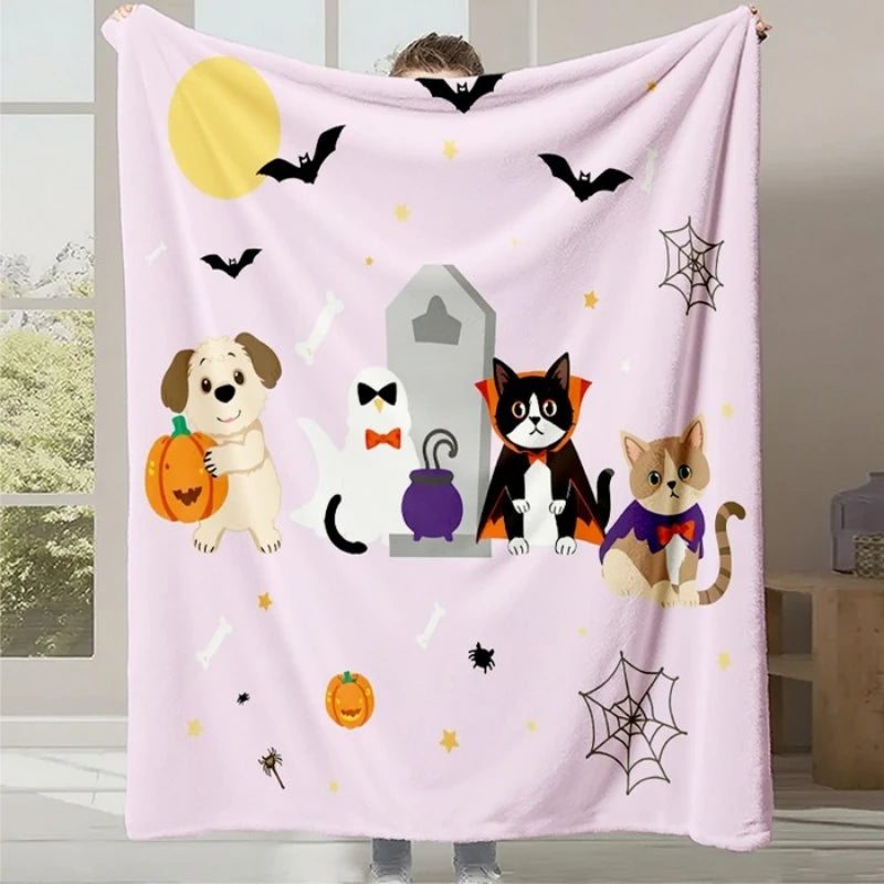 Cette image représente une couverture ou un plaid rose pâle décoré de motifs d'Halloween, notamment des chauves-souris, des citrouilles, des toiles d'araignée et différents animaux comme un chien, un chat et un chat noir en costumes.