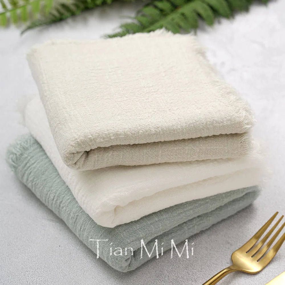 Serviettes de bain blanches et grises avec un ornement doré sur le côté, sur fond d'éléments végétaux.