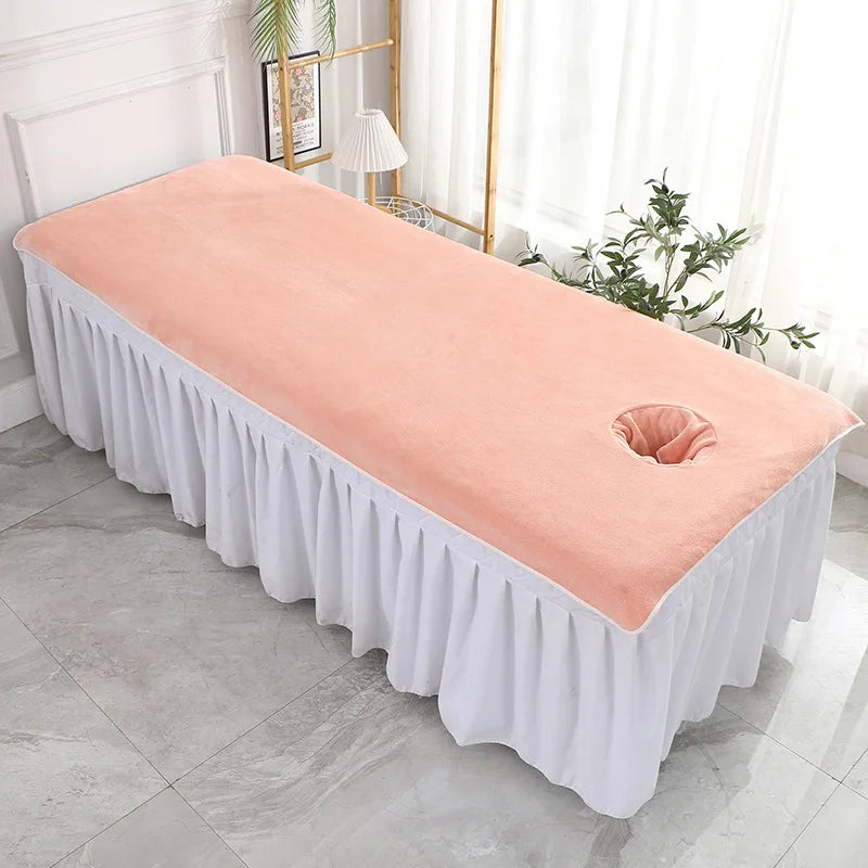 Un lit de massage rose pâle avec une couverture élégante, dans un cadre spacieux et lumineux.