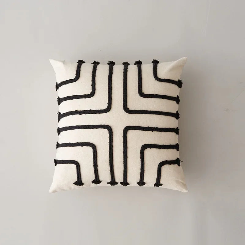 Coussin décoratif blanc et noir avec un motif géométrique abstrait.