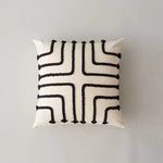 Coussin décoratif blanc et noir avec un motif géométrique abstrait.