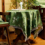 La nappe décorative verte foncée avec des motifs de bambou est posée sur une table en bois, créant une atmosphère tropicale et chaleureuse dans cette pièce.
