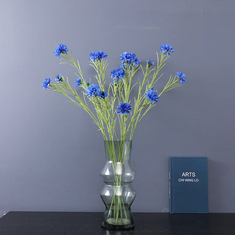 décoration intérieure bouquet fleurs artificielles bleues blanches roses longues tiges vertes vase transparent festonnée