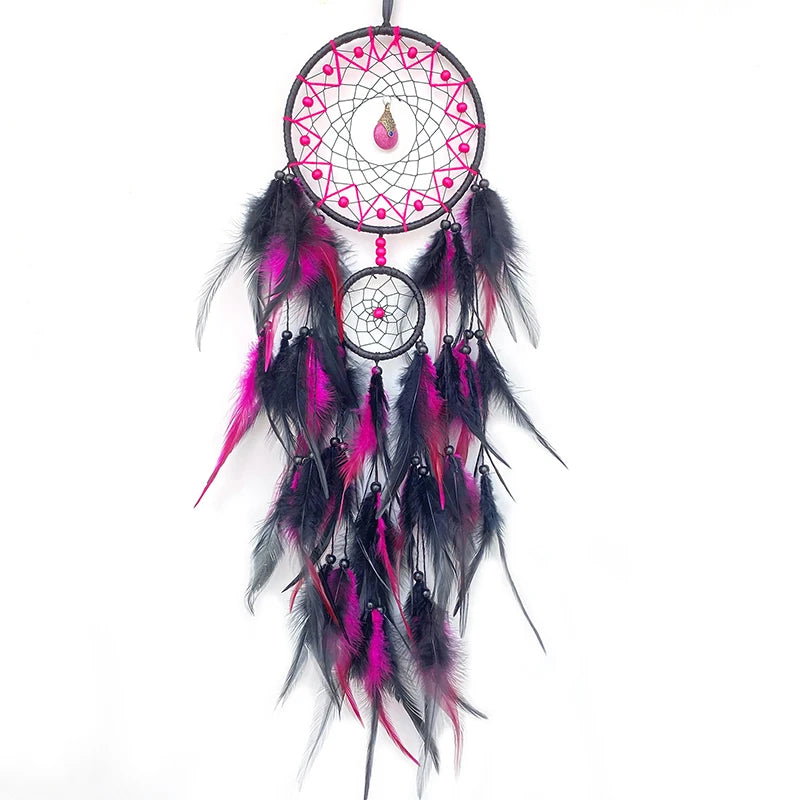 Cette image montre un attrape-rêves décoratif composé d'un cercle tressé avec des plumes de couleur rose et noire qui pendent du centre.