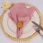 Une belle serviette rose avec une fleur décorative sur une belle assiette tressée.