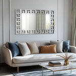 Un design moderne et élégant de salon avec un canapé moelleux, des coussins de couleurs apaisantes et un miroir décoratif au style géométrique.
