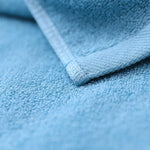 Un gros plan détaillé sur le tissu moelleux et bleu d'une serviette, révélant la texture et le motif caractéristiques d'un textile de haute qualité.