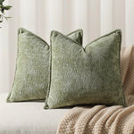 Trois coussins décoratifs vert olive avec une texture en relief, placés sur un canapé beige dans un intérieur cosy.