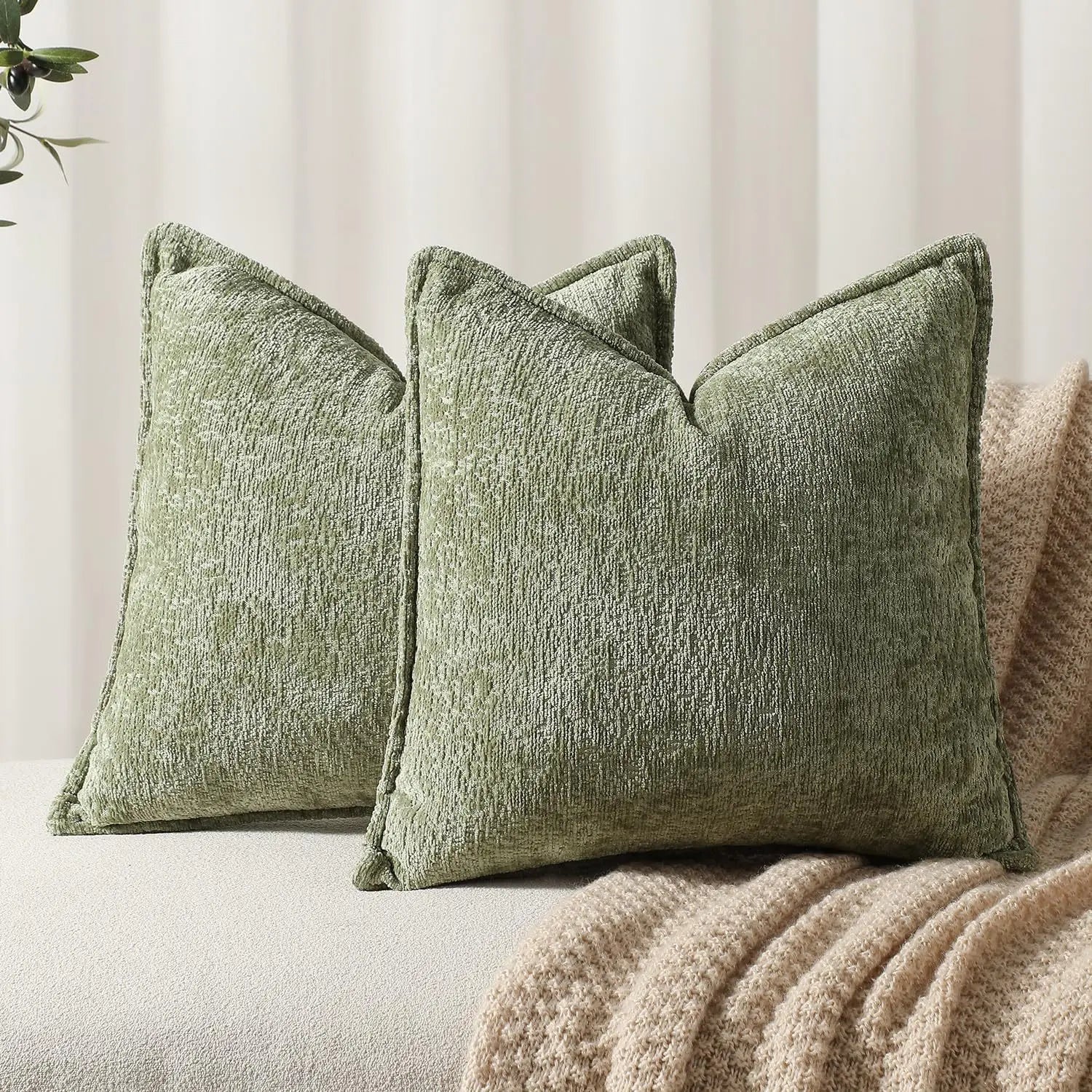 Trois coussins décoratifs vert olive avec une texture en relief, placés sur un canapé beige dans un intérieur cosy.