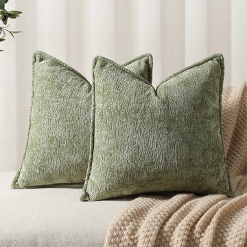Trois coussins décoratifs vert olive avec une texture en relief, placés sur un canapé beige dans un intérieur cosy.