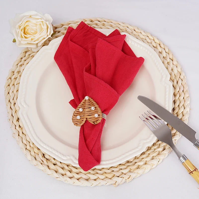 Ensemble de table élégant avec assiette blanche, serviette rouge et jolie fleur blanche posée sur un tapis en fibres naturelles.