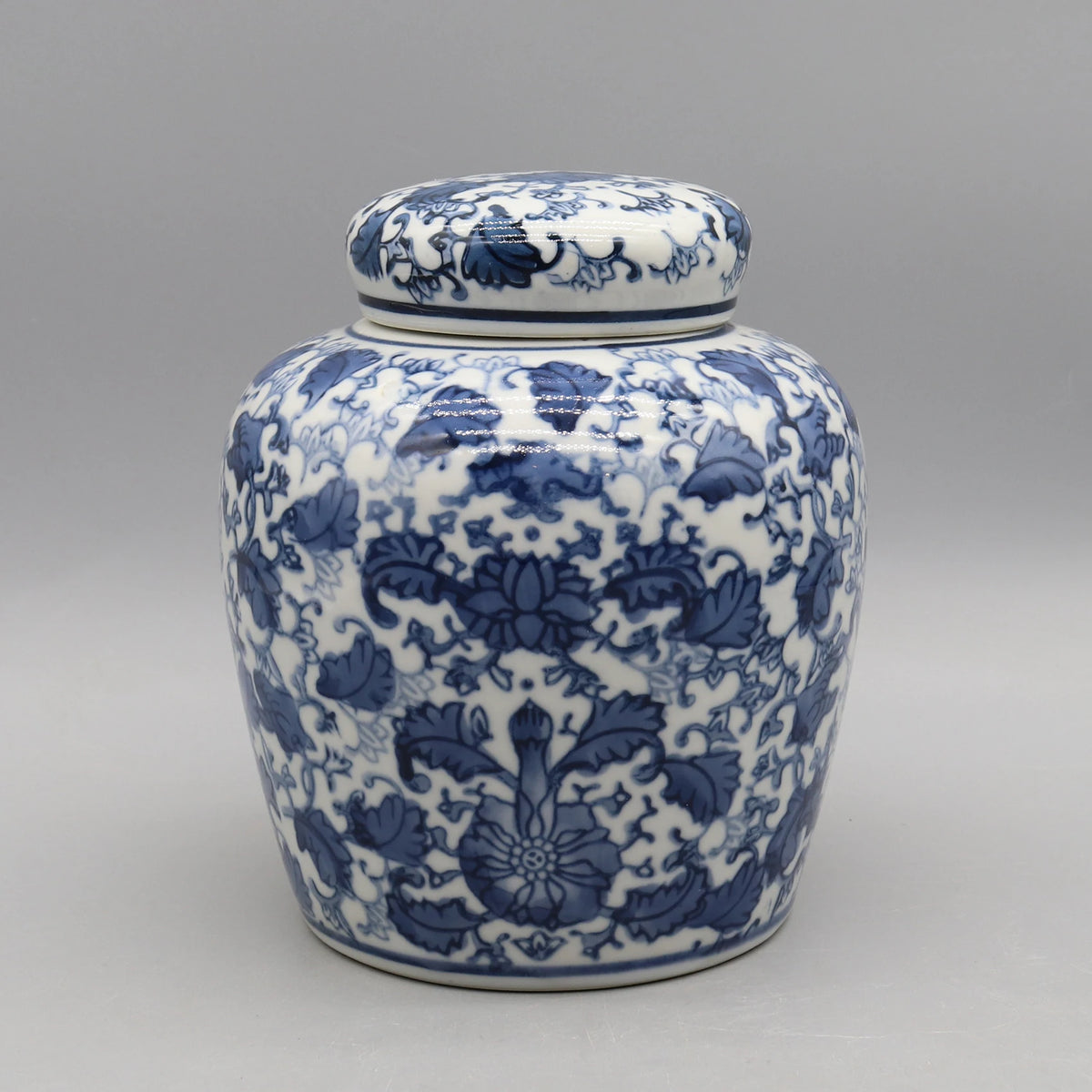 Pot de porcelaine décoré de motifs floraux bleus et blancs sur un fond gris neutre.