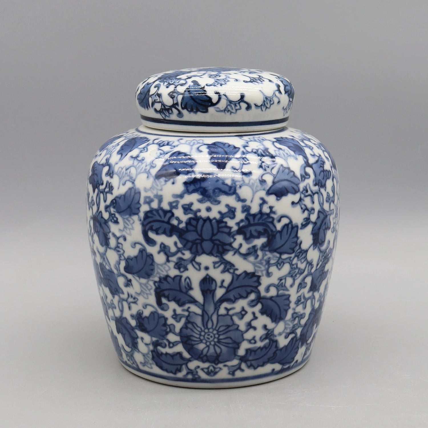 Pot de porcelaine décoré de motifs floraux bleus et blancs sur un fond gris neutre.