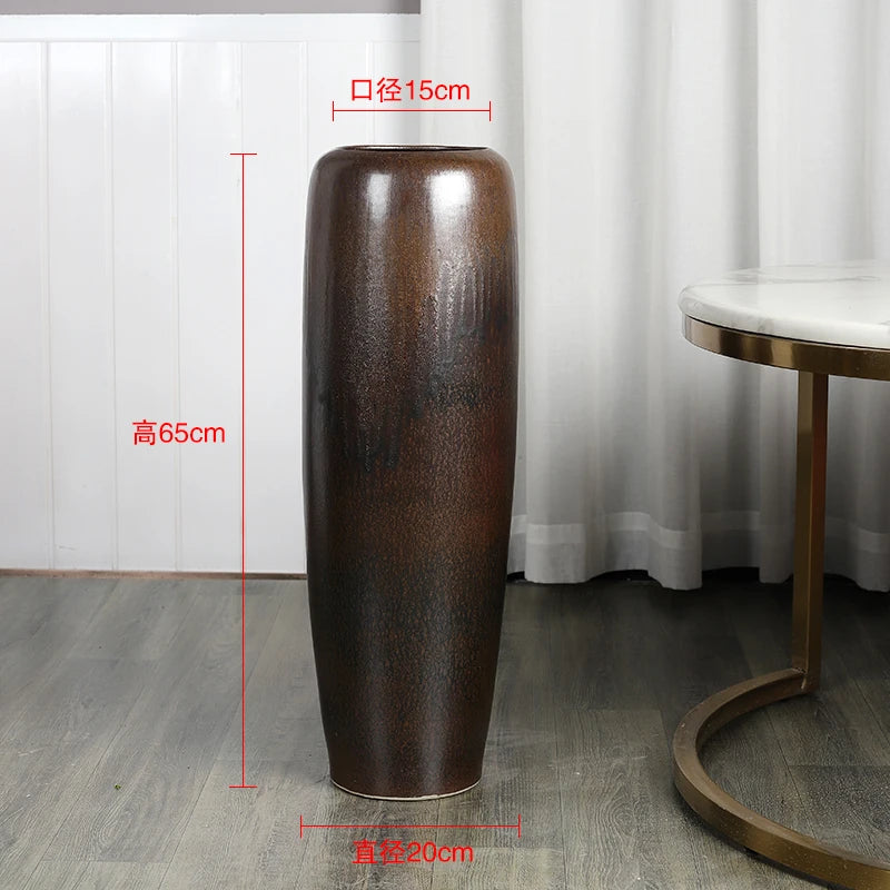 Un grand vase en céramique brun foncé de style moderne et épuré, posé sur le sol dans un intérieur élégant.