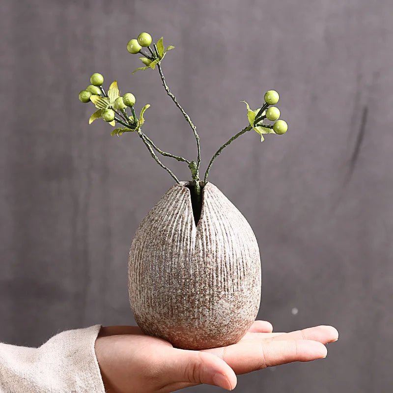 Vase en terre cuite de style japonais avec arrangement floral abstrait sur table vintage