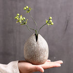 Vase en terre cuite de style japonais avec arrangement floral abstrait sur table vintage