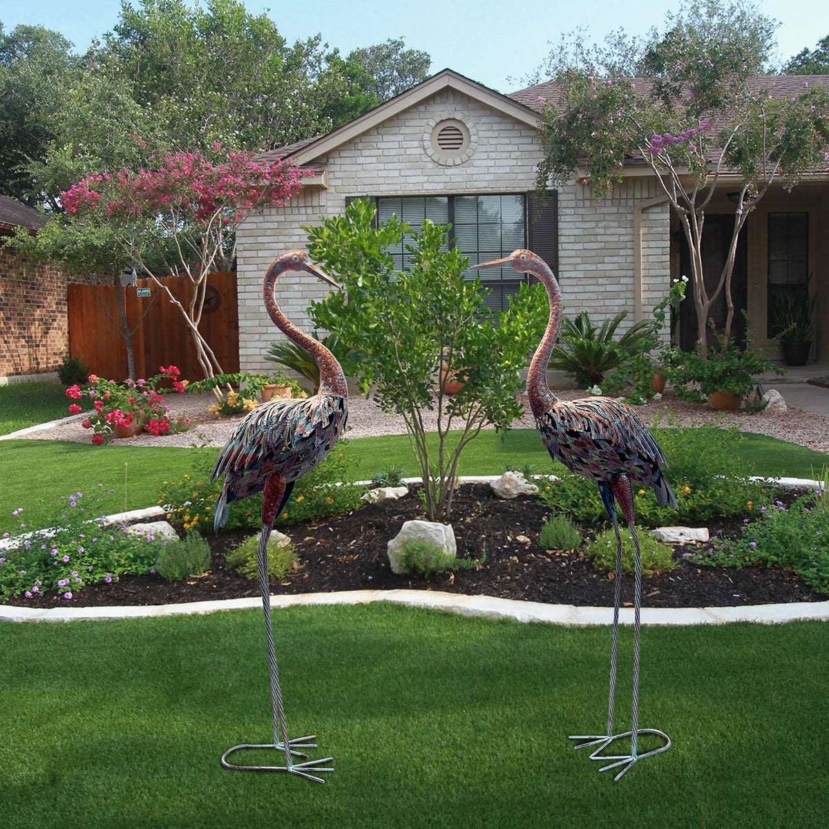 statues oiseaux grue marron rouge gris vert métal patiné jardin decoratif fleurs tulipes plantes