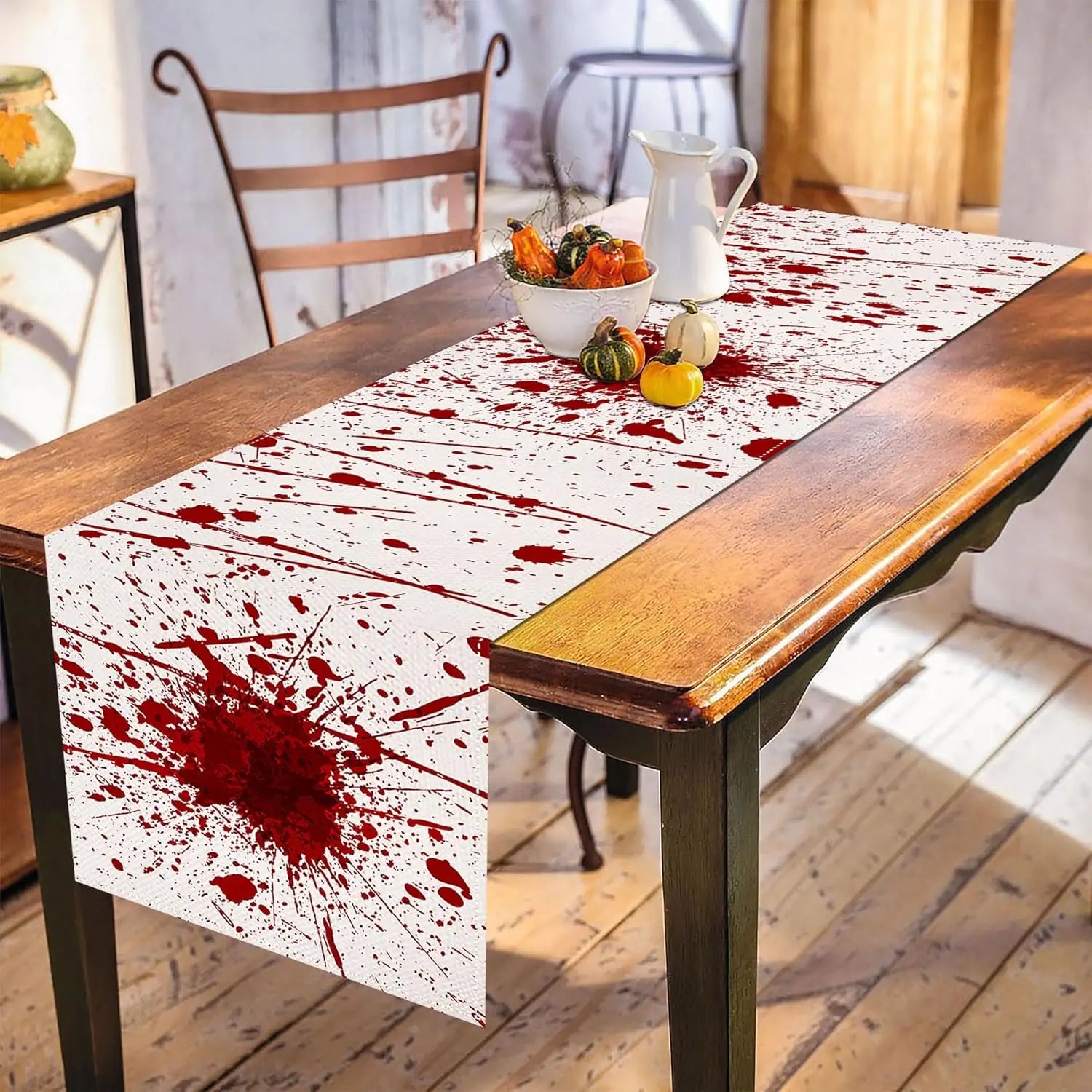 La table en bois est recouverte d'un chemin de table coloré avec des taches rouges, créant une ambiance rustique et accueillante dans la pièce.