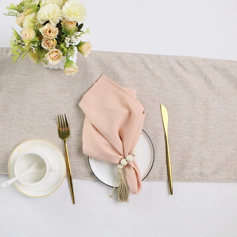 Un arrangement floral élégant décore la table de service, entouré de couverts dorés et d'une belle serviette rose.