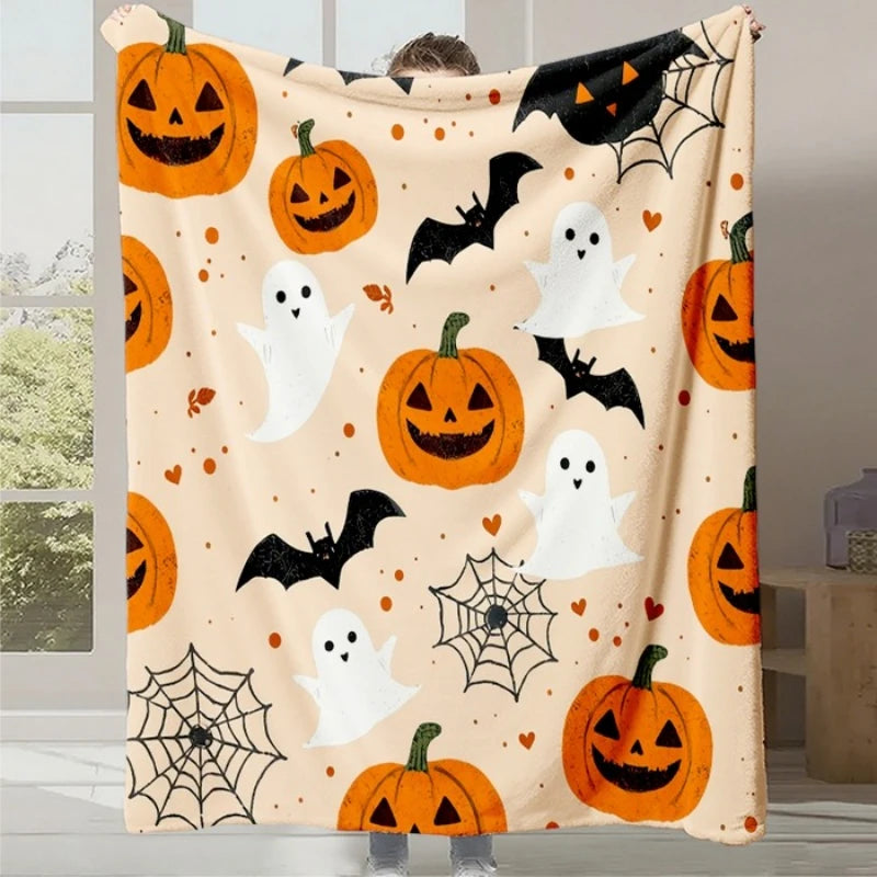 Une couverture blanche avec des citrouilles d'Halloween, des fantômes et des chauve-souris, créant une ambiance festive et accueillante pour la saison d'Halloween.