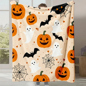 Une couverture blanche avec des citrouilles d'Halloween, des fantômes et des chauve-souris, créant une ambiance festive et accueillante pour la saison d'Halloween.