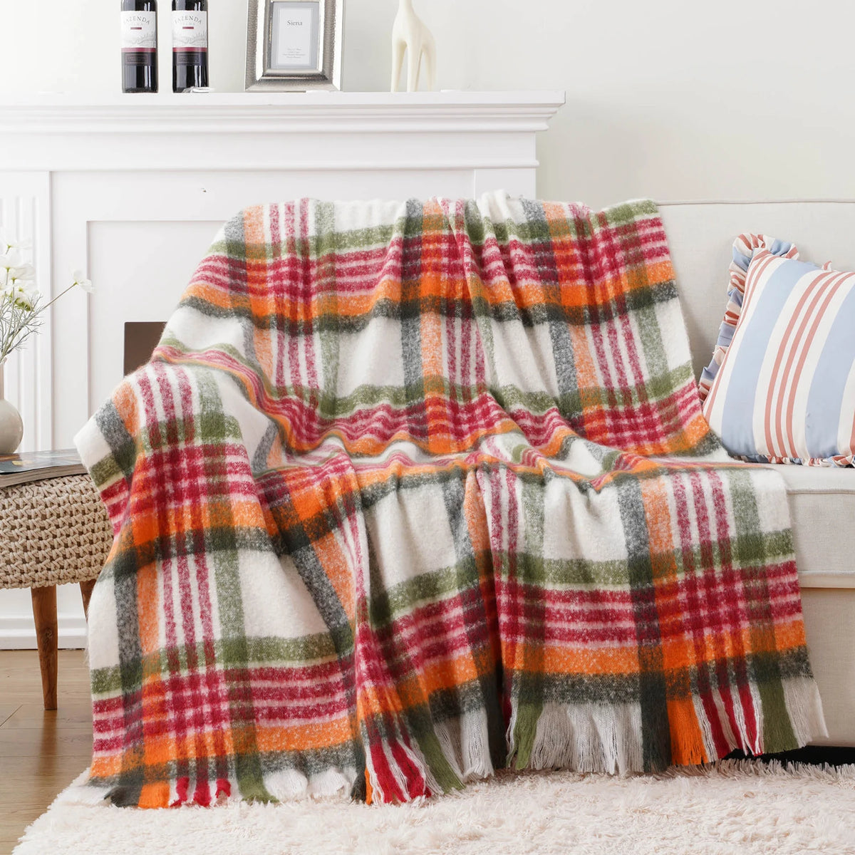 Une couverture à motif de tartan coloré, composée de rayures rouges, vertes et oranges sur un fond blanc, idéale pour réchauffer l'atmosphère d'un intérieur.