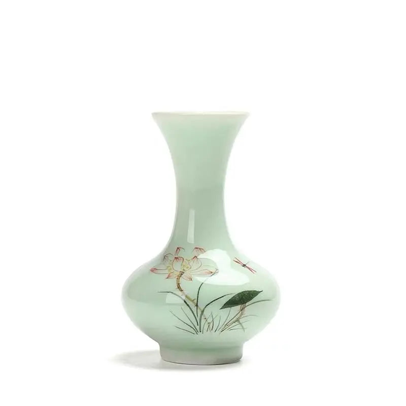 Un joli vase en céramique vert clair décoré avec des fleurs et des libellules.
