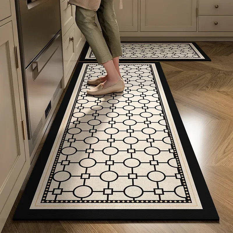 Un tapis de cuisine au motif géométrique noir et blanc, avec des formes circulaires et rectangulaires, posé sur un sol en bois, complétant harmonieusement l'espace de la cuisine.