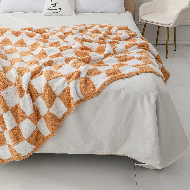 Couverture orange et blanche à motifs géométriques posée sur un lit dans une chambre élégante.