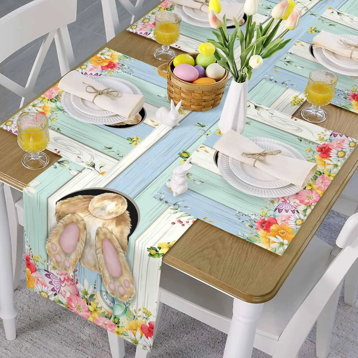 Une table de printemps colorée avec des décorations de Pâques, un bouquet de tulipes, des verres de jus et des assiettes fleuries.