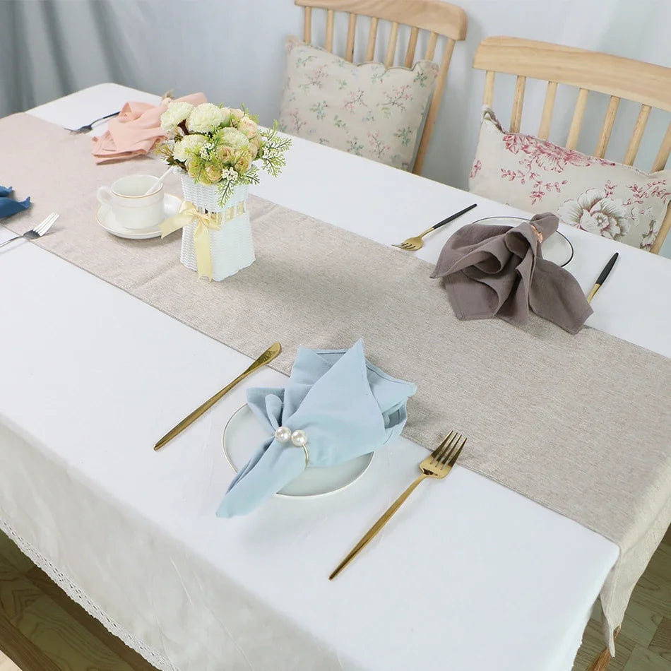 Une table de salle à manger élégante avec un bouquet de fleurs, des serviettes de table, des couverts dorés et un décor floral dans une ambiance chaleureuse et cosy.