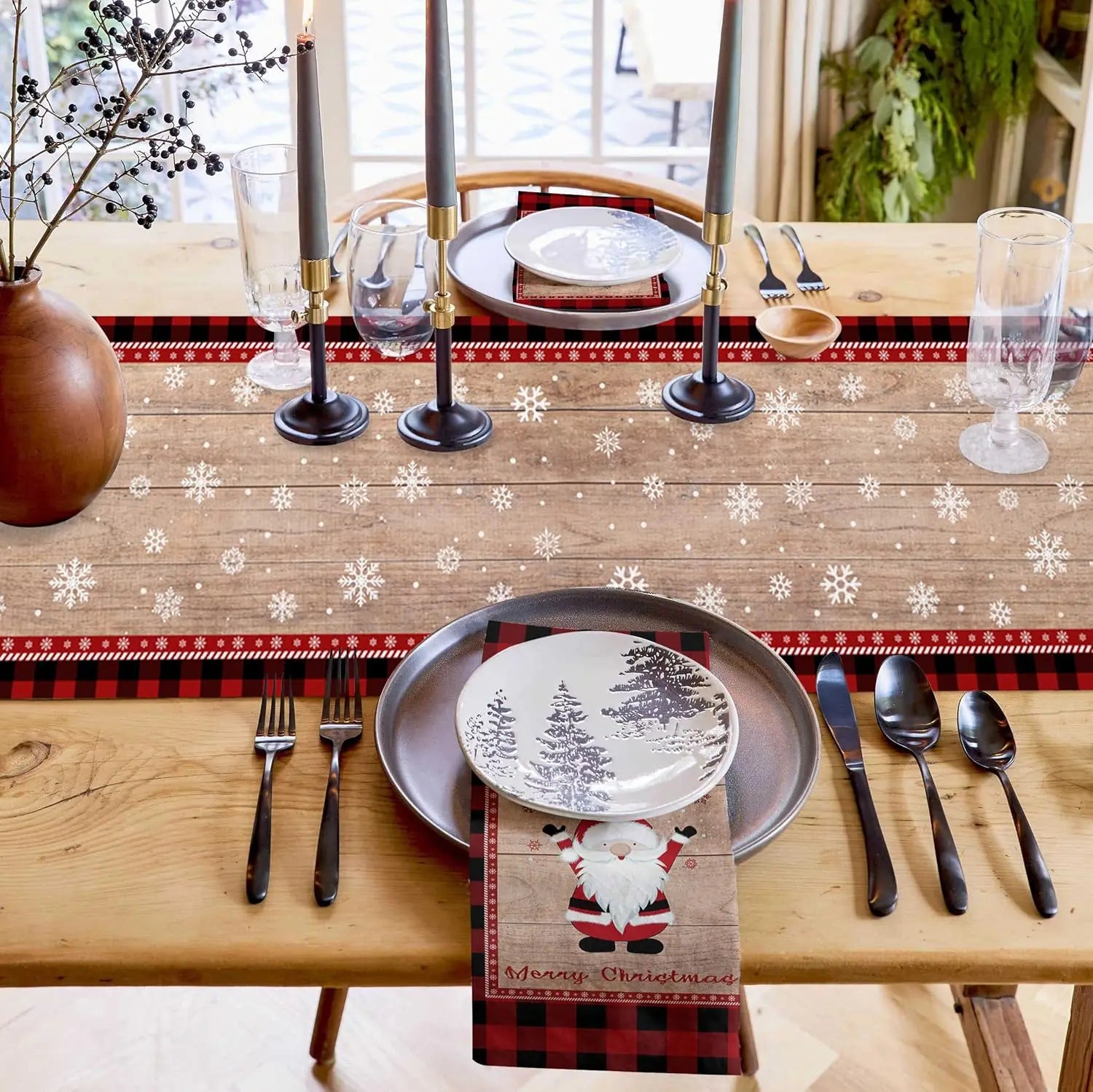 Ensemble de table de Noël avec des décorations festives, une nappe à motifs de flocons de neige et une vaisselle élégante, créant une ambiance chaleureuse et accueillante pour un repas des fêtes.