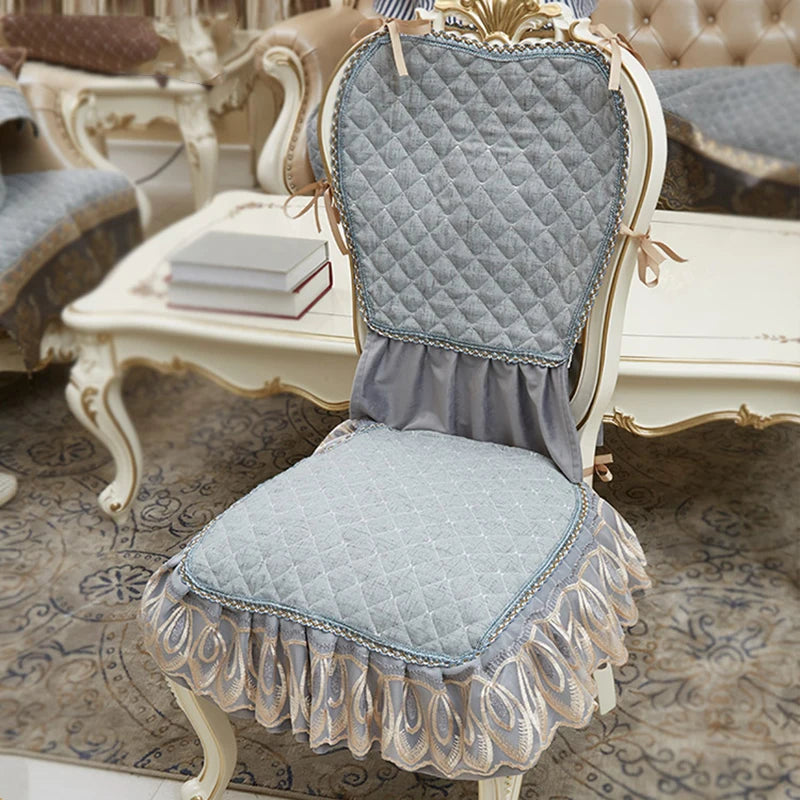 Chaise vintage élégante en bois blanc avec coussin matelassé gris et volants décoratifs, posée sur un tapis de sol ornementé, dans un cadre intérieur raffiné.
