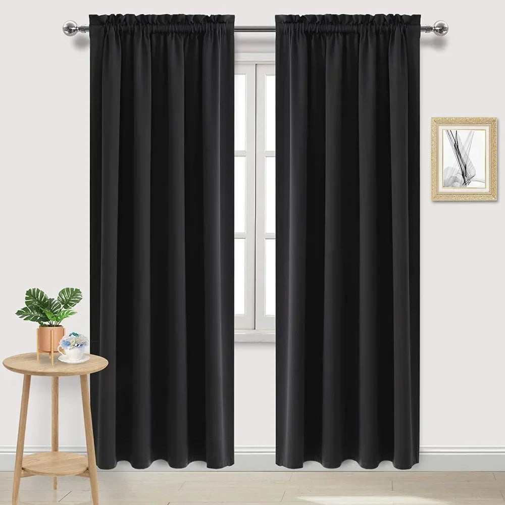 Paire de rideaux noirs occultants installés sur une tringle dans un salon lumineux avec mur blanc et table d'appoint en bois.