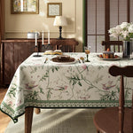 Une scène de salle à manger chaleureuse et invitante, avec une table recouverte d'une nappe florale et décorée de chandelles, de fleurs et d'un gâteau.