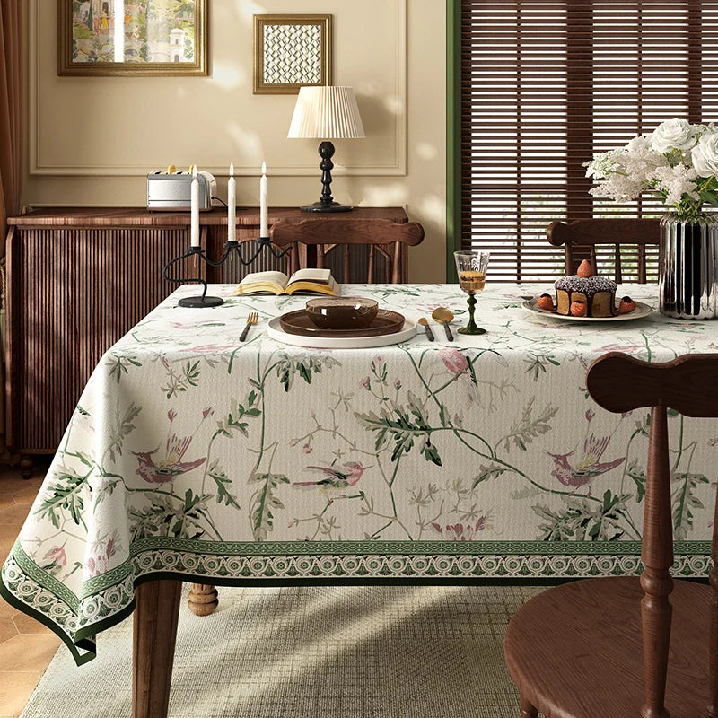 Une scène de salle à manger chaleureuse et invitante, avec une table recouverte d'une nappe florale et décorée de chandelles, de fleurs et d'un gâteau.