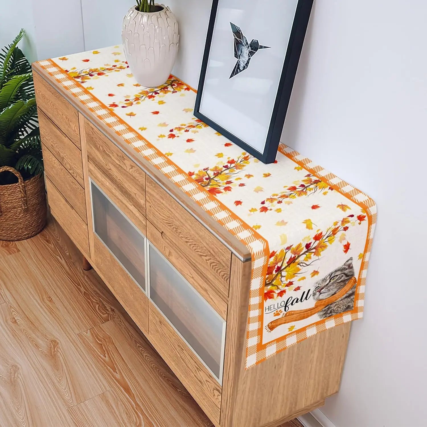 La console en bois avec des motifs de feuilles d'automne et une décoration de fleurs crée une ambiance chaleureuse et accueillante dans cette pièce.